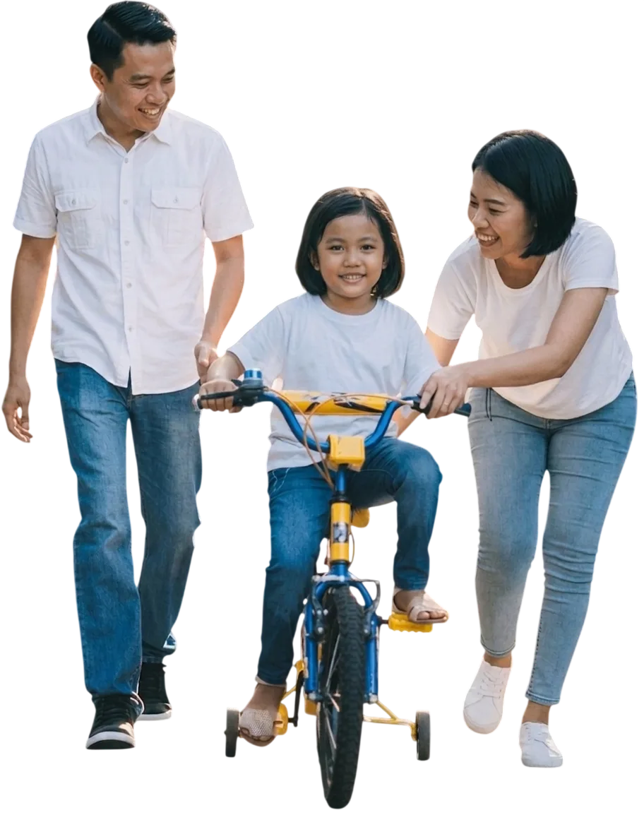 Smiling family helping a young child ride a bicycle